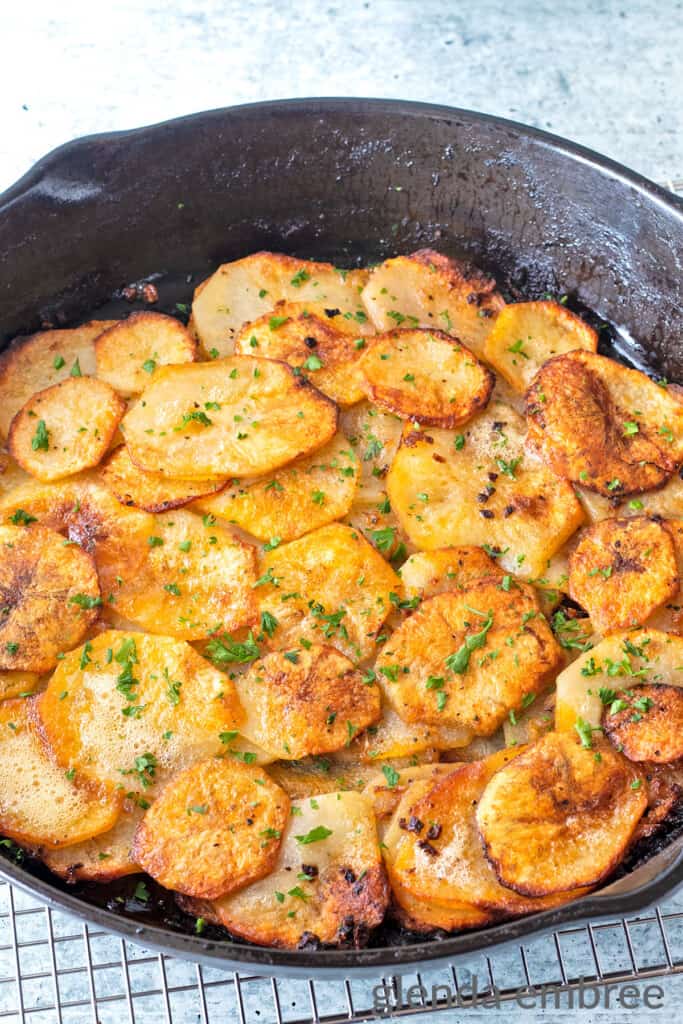 Fried Potatoes and Onions garnished with chopped parsley in a cast iron skillet