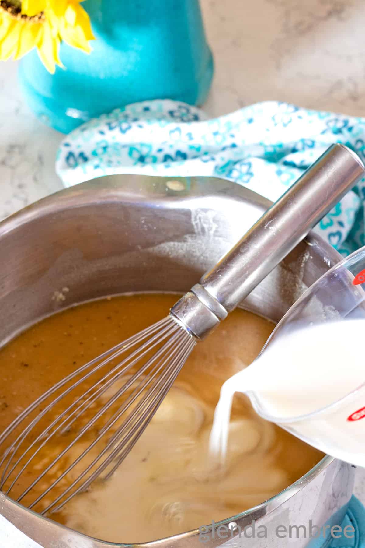 adding milk to sauce pan with roux and chicken broth