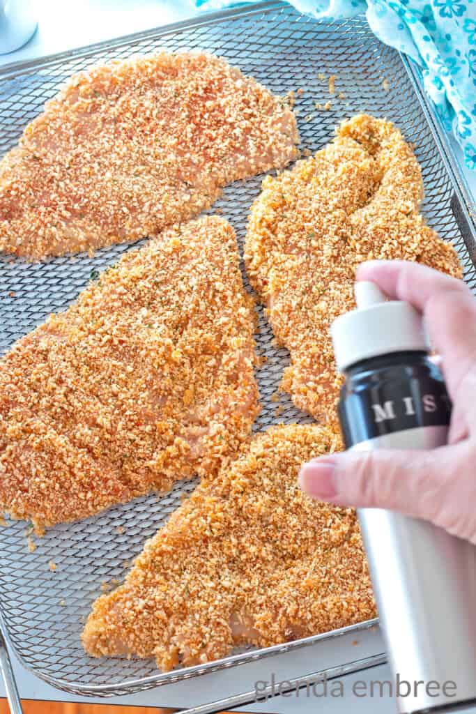Spraying breaded chicken cutlets with oil before air frying