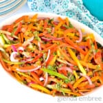 Bell Pepper Salad in a white oval serving bowl on a marble countertop. Salad has julienned bell peppers, red onions and cucumbers, tossed with chopped fresh herbs and a red wine vinaigrette