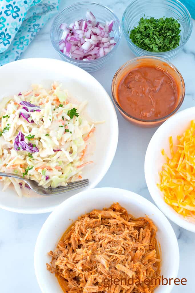 Pulled Pork Taco Ingredients - pulled pork, grated cheese, coleslaw, bbq sauce and minced red onions