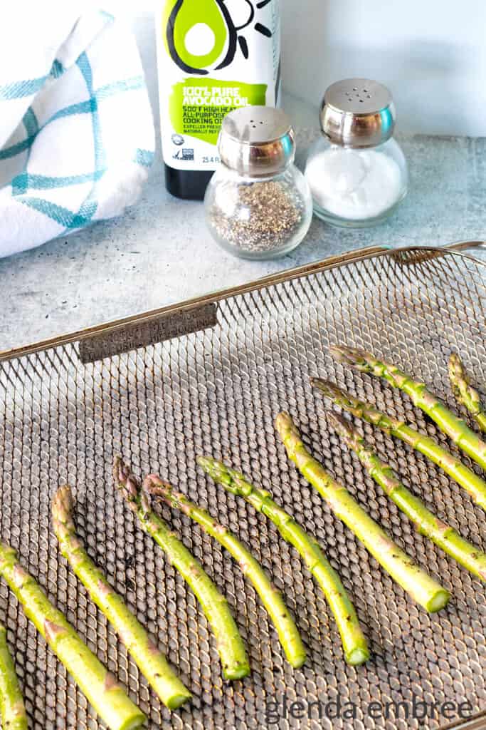 Fresh asparagus spears tossed in oil, salt and pepper and then placed on an air fryer rack.