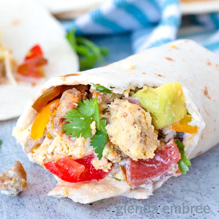 Breakfast taco with bites out held in a hand with unrolled taco in background