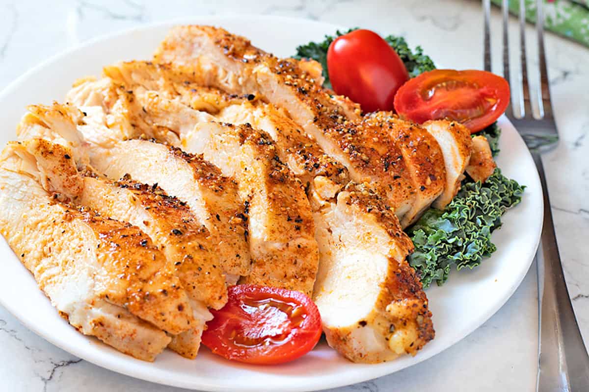 Perfect Baked Chicken Breasts on a white plate with garnish