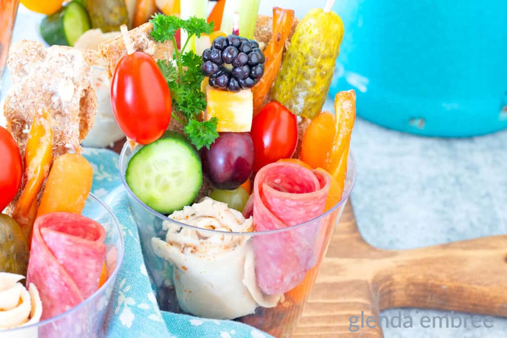 Individual charcuterie cups decoratively filled with deli meat, veggies, crackers, pretzels, crudites, cheese, nuts and berries.