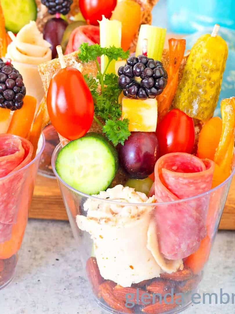 Individual charcuterie cups decoratively filled with deli meat, veggies, crackers, pretzels, crudites, cheese, nuts and berries.
