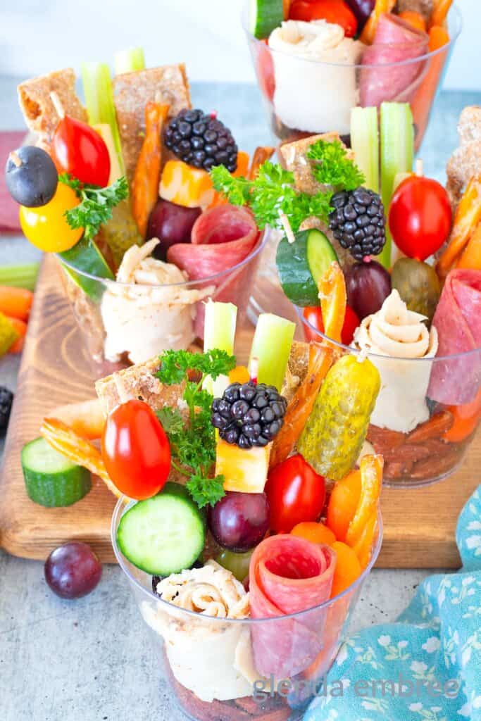 Individual charcuterie cups decoratively filled with deli meat, veggies, crackers, pretzels, crudites, cheese, nuts and berries.