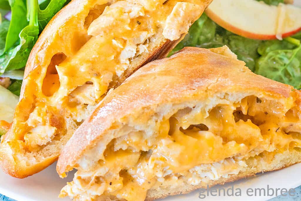 Quick and easy recipe for Buffalo Ranch Chicken Melts on a white plate with spinach salad.