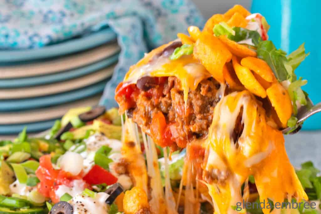Walking Taco Casserole being served and the cheese is stretching from the casserole dish to the serving spoon