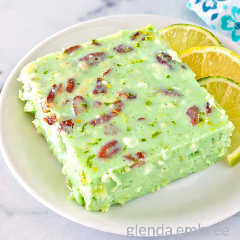 Lime Jello Salad with Cottage Cheese on a white plate with lime and lemon slices.