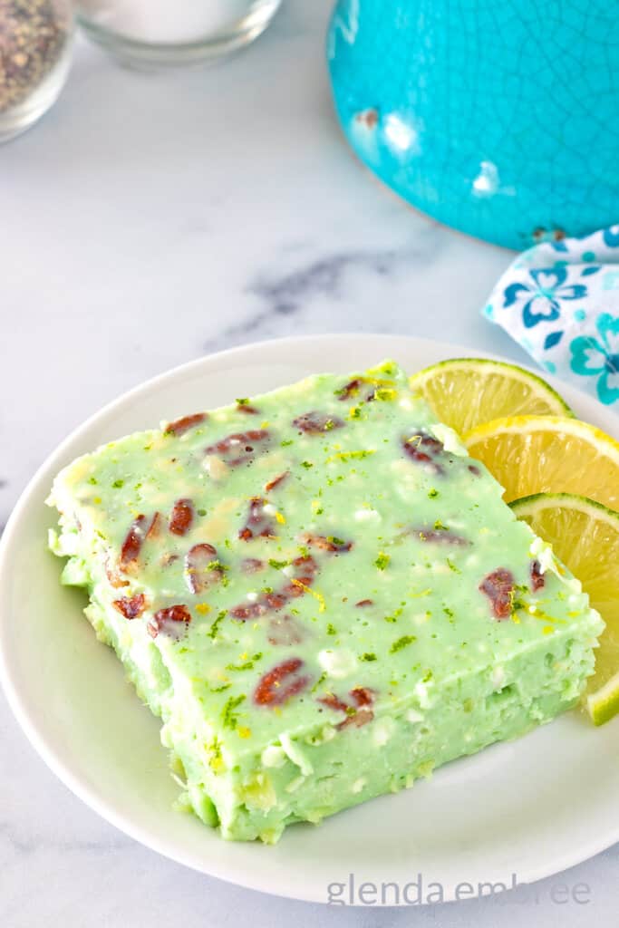 Lime Jello Salad with Cottage Cheese on a white plate with lime and lemon slices.