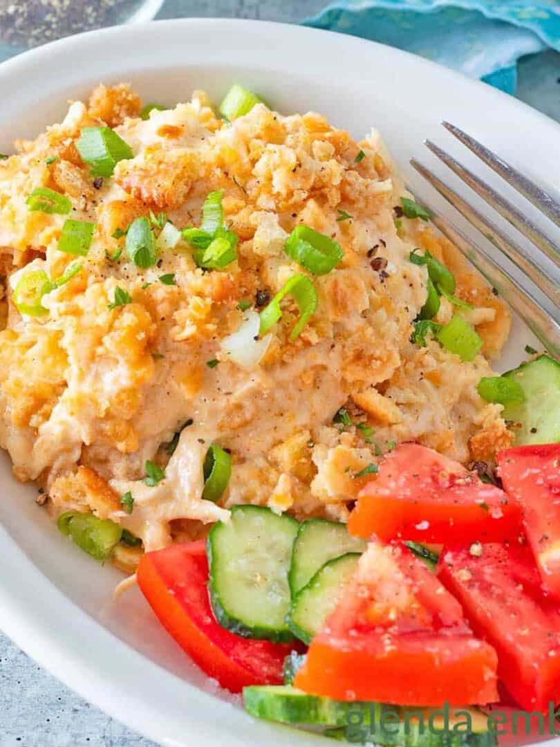 Million Dollar Chicken Casserole in a white dish with cucumber and tomato salad.