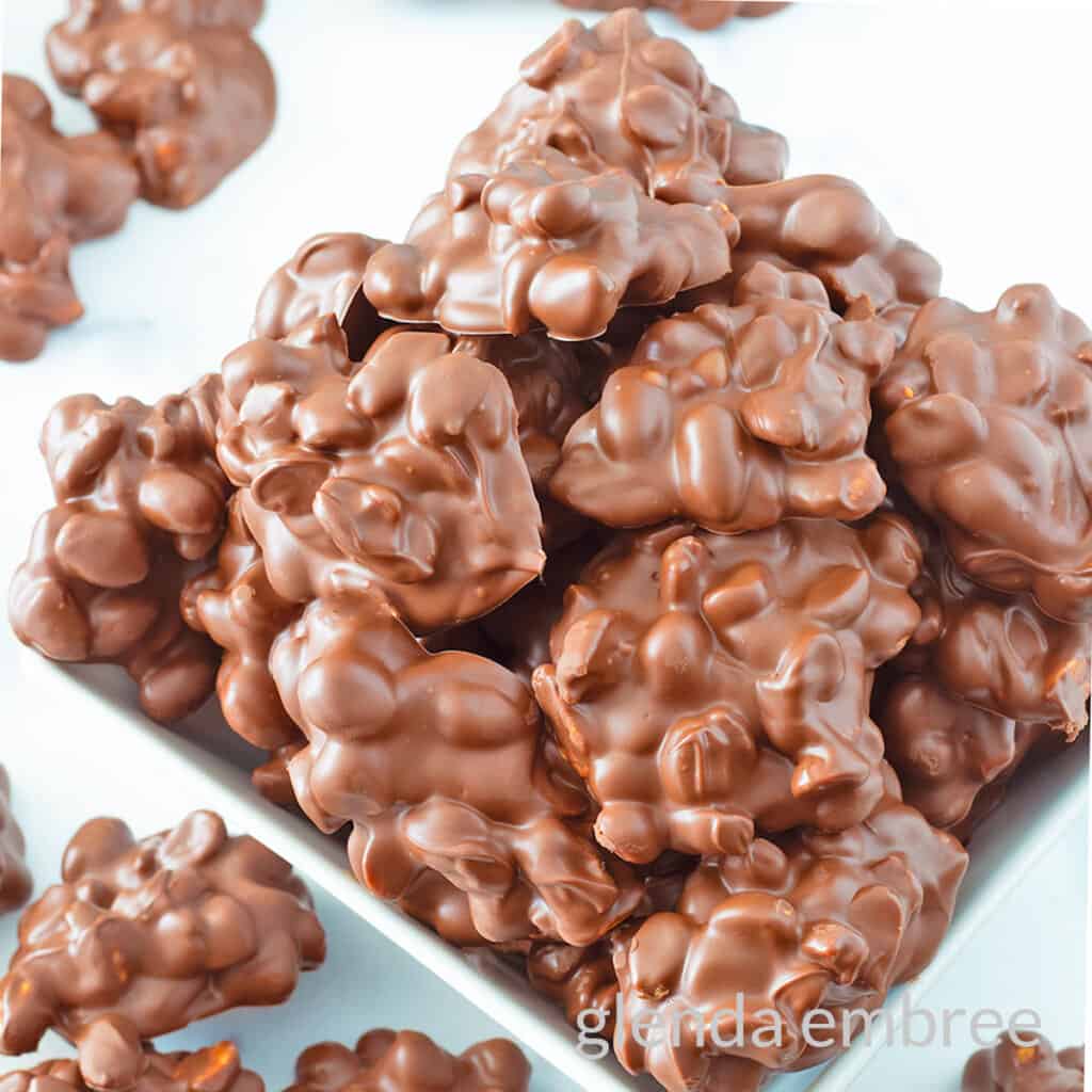 Chocolate Peanut Clusters in a square ceramic bowl.