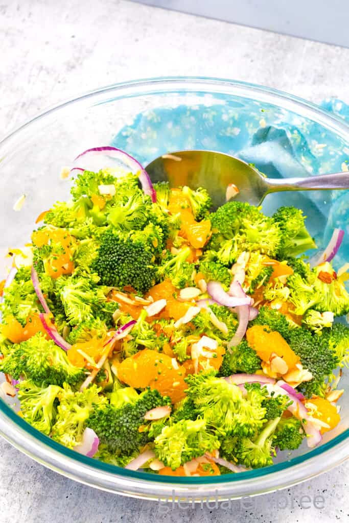 Crunchy Broccoli Salad ingredients tossed together in a clear mixing bowl.