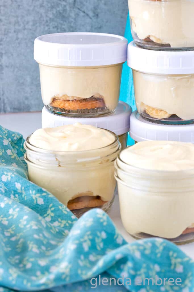 Banana Pudding Cups in clear glass mason jars on a marble countertop.