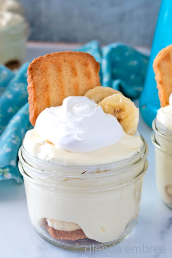 Banana Pudding Cups in clear glass mason jars on a marble countertop.