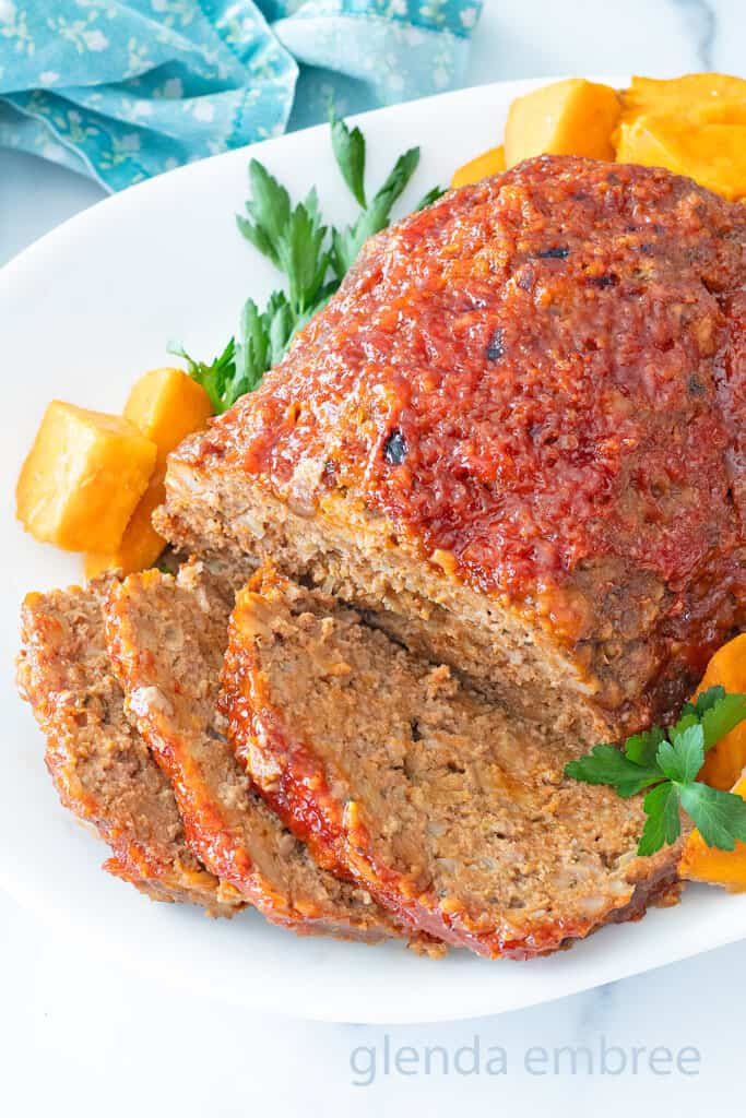 Stove Top Stuffing Meatloaf (Slow Cooker Meatloaf) served on a white platter with sweet potato chunks.