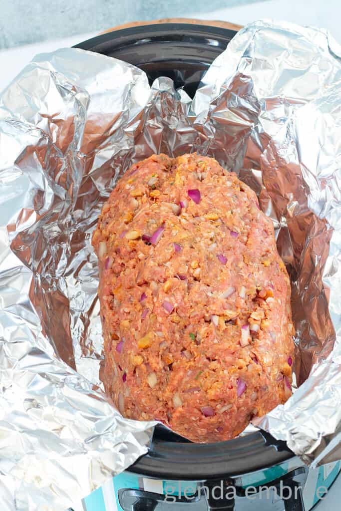 Stove Top Stuffing Meatloaf (Slow Cooker Meatloaf) mixture formed into a loaf and placed in a foil lined crock-pot.