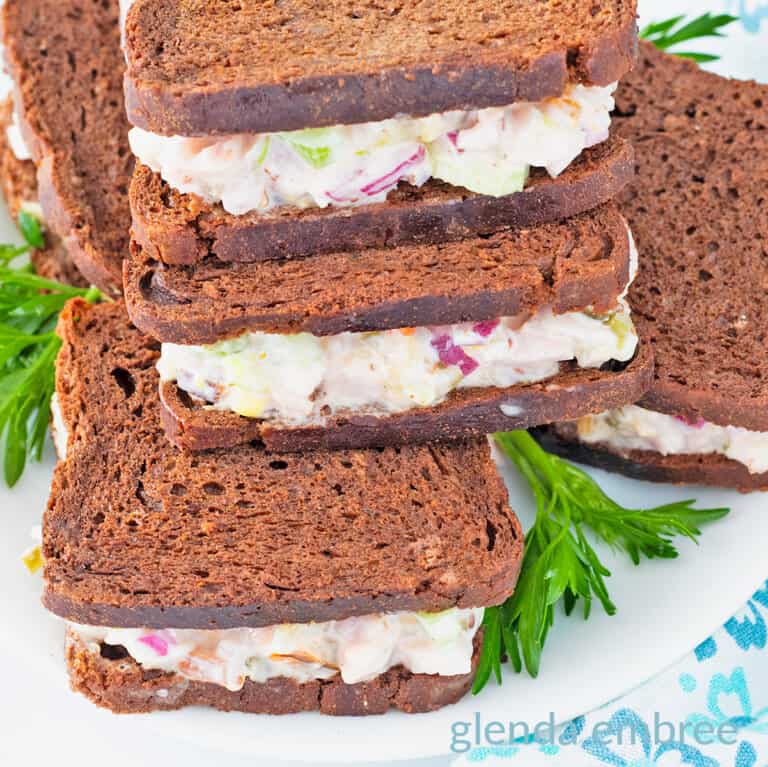 Mini ham salad sandwiches on pumpernickle rye squares.