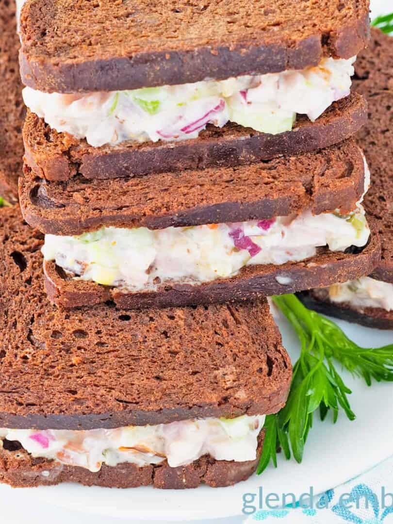 Mini ham salad sandwiches on pumpernickle rye squares.