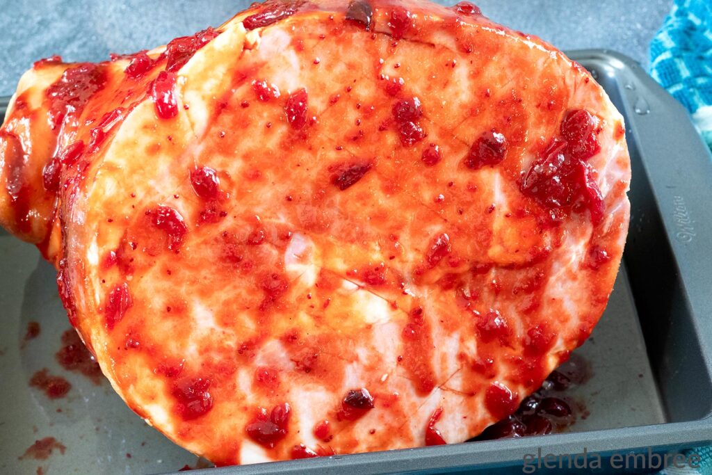 Baked Ham with Cranberry Glaze ready for the oven.  The cranberry glazed ham has been coated with a glaze made from whole berry cranberry sauce, yellow mustard and dark brown sugar.