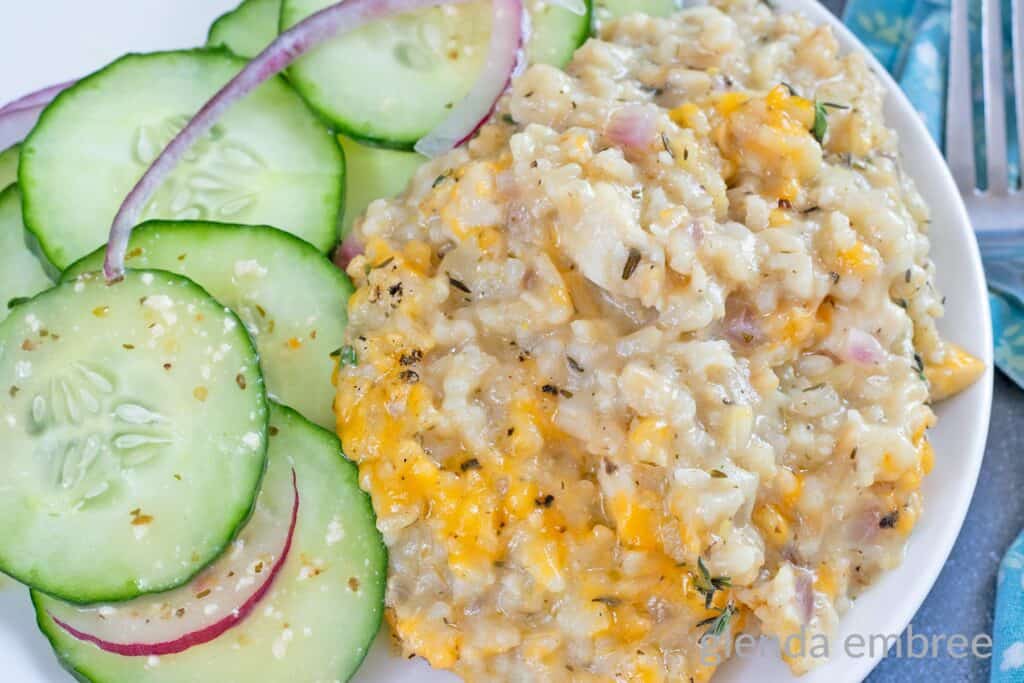 Creamy One Pan Chicken and Rice on a white plate with a cucumber salad.