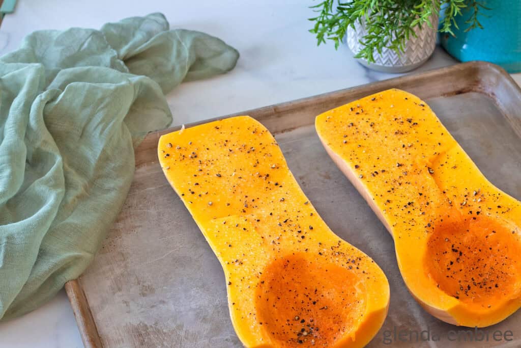 Halved butternut squash with seeds scooped out and then brushed with oil and sprinkled with salt and pepper.