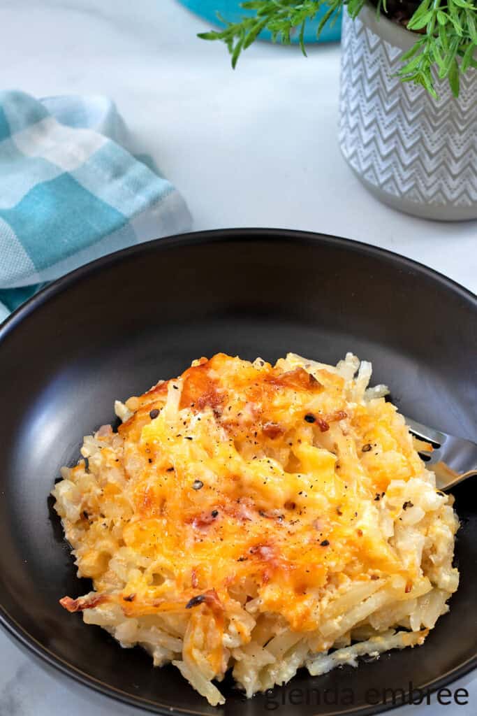 Hashbrown Casserole aka Funeral Potatoes in a black ceramic bowl.