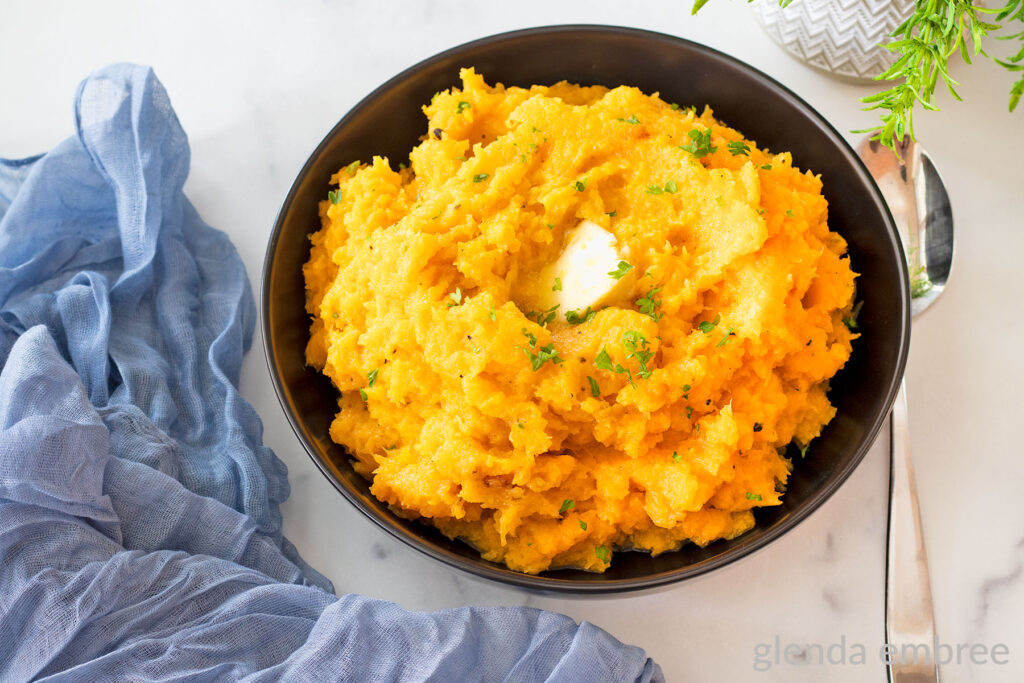 Mashed Butternut Squash in a black serving bowl on a marble countertop.