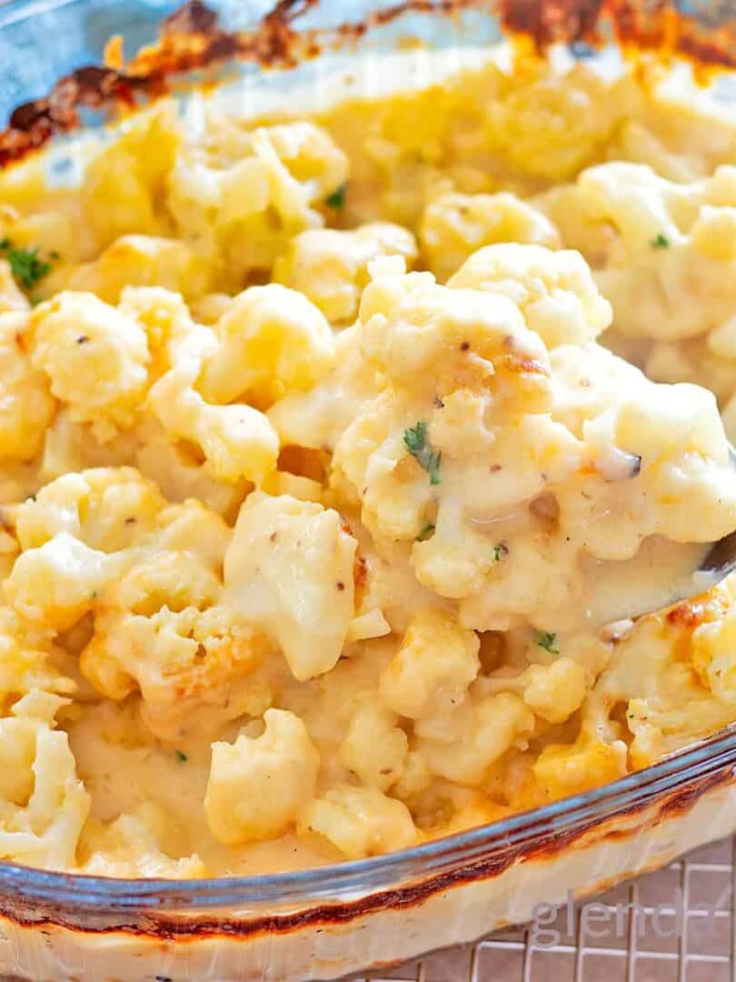 Baked Cauliflower Gratin, (Cauliflower with Cheese Sauce), Cauliflower Cheese, Cheesy Cauliflower in a clear glass baking dish with a sprinkle of chopped parsley.