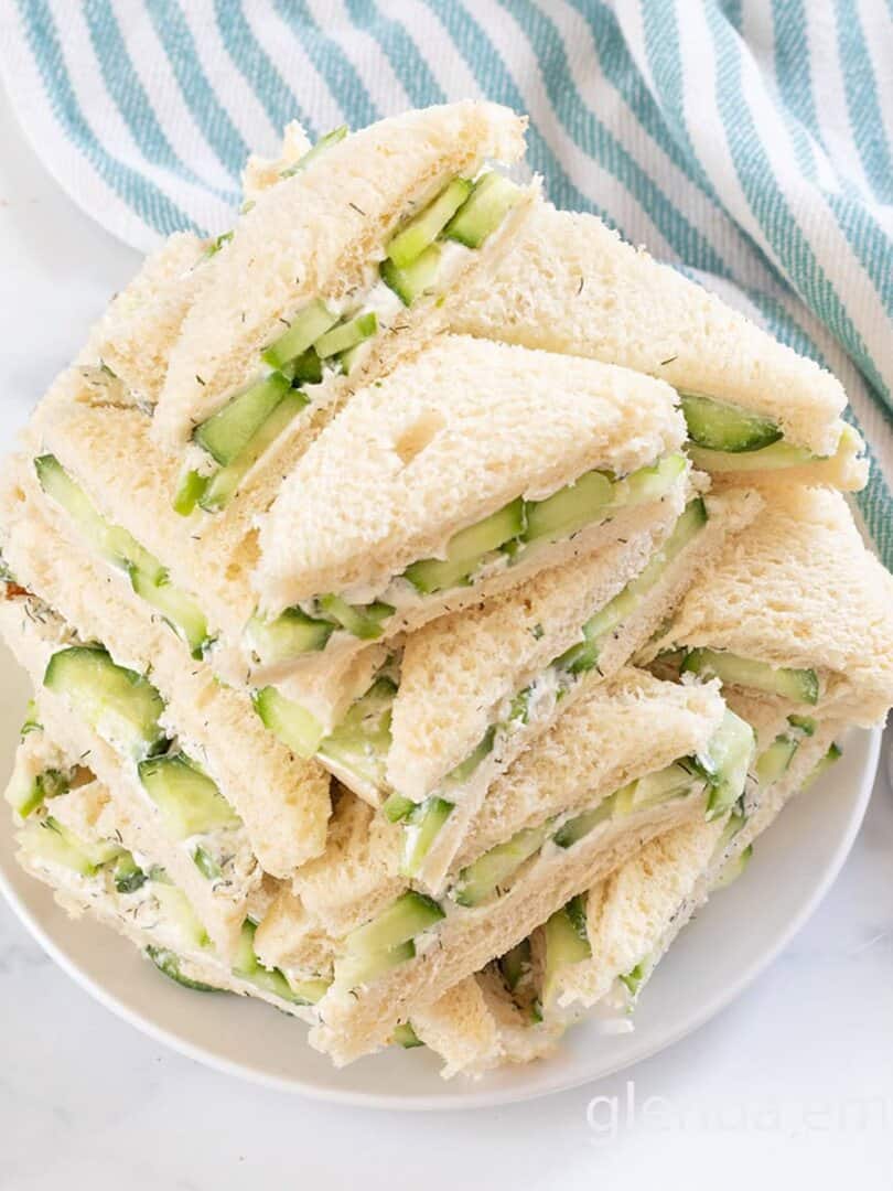 Cucumber Sandwiches stacked on a white plate.