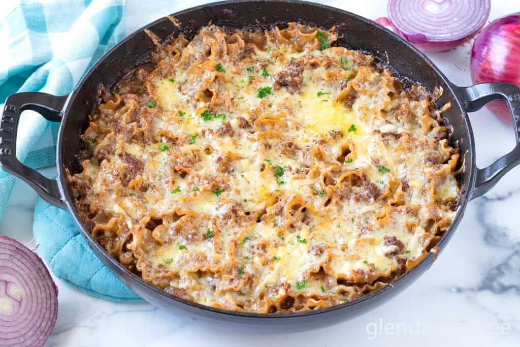 Completed French Onion Beef and Noodles Casserole in a cast iron skillet on a marble counter.