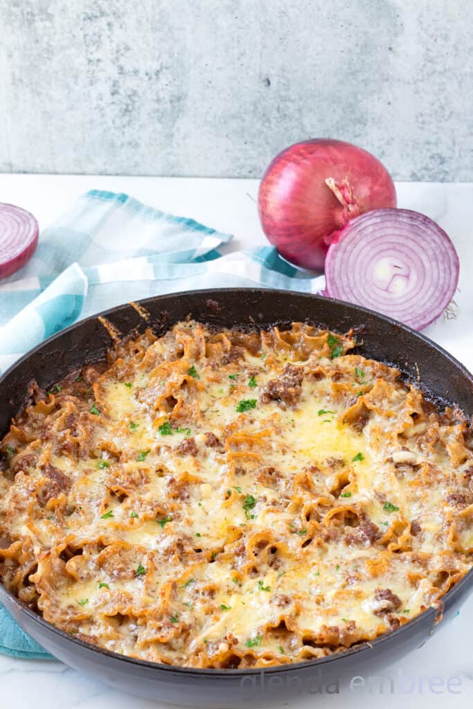 French Onion Beef and Noodle Casserole in a cast iron skillet on a marble counter.