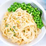 Chicken tetrazzini served in a white ceramic bowl with buttered peas.