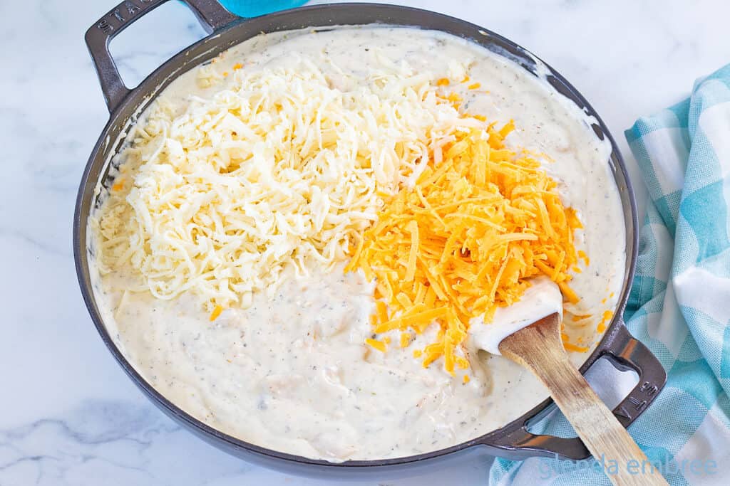 Adding grated cheese to chicken tetrazzini sauce.