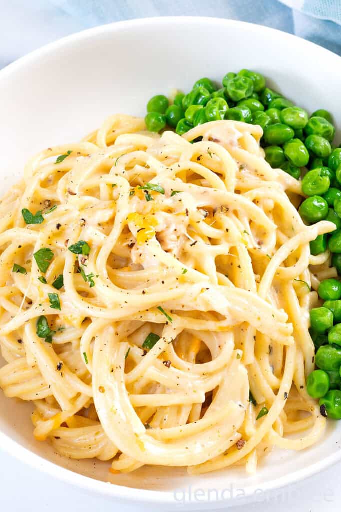 Chicken tetrazzini served in a white ceramic bowl with buttered peas.