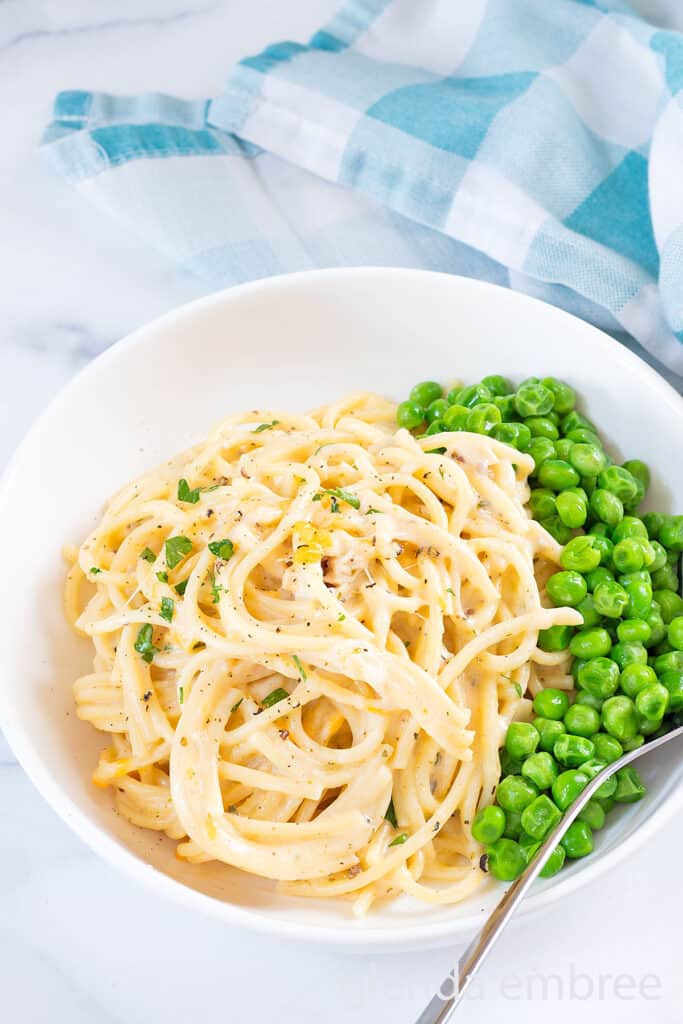 Chicken tetrazzini served in a white ceramic bowl with buttered peas.