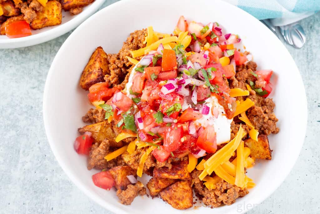 Taco bowl with taco potatoes in a white ceramic bowl on a concrete countertop.