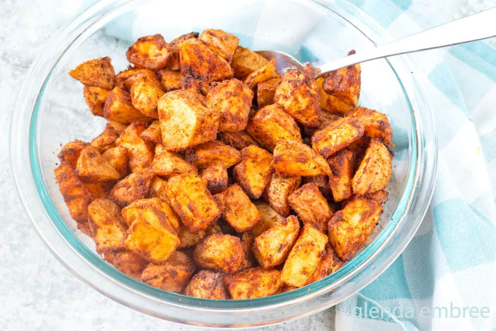 Roasted Taco Potatoes (Taco Fries) in a clear glass bowl on a concrete countertop.
