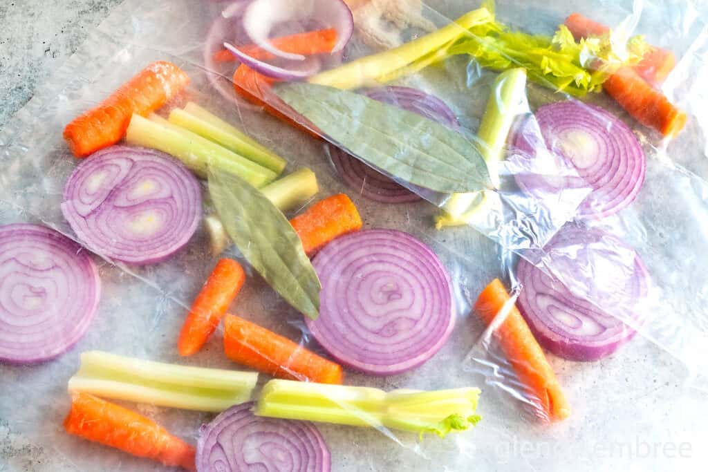 Cut vegetables, red onion, carrots and celery, along with two bay leaves all inside a turkey roasting bag.