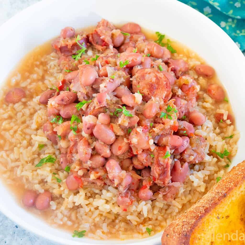 Red Beans and Rice served in a white ceramic bowl with a slice of toasted garlic bread.