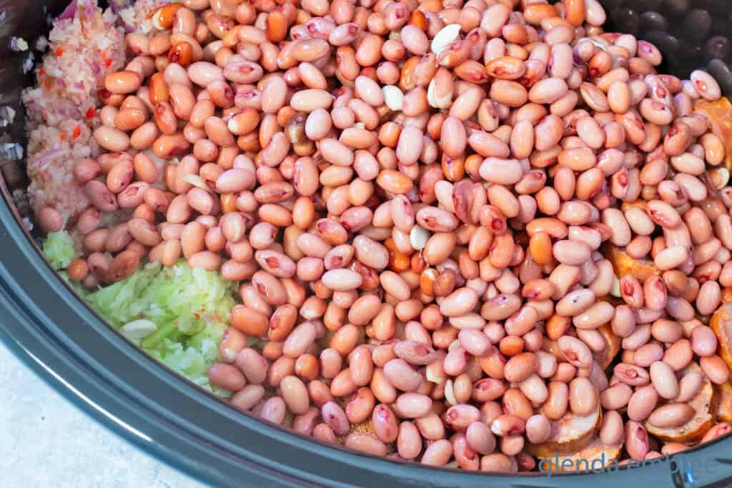 Adding red beans over the vegetables and spices for Slow Cooker Red Beans and Rice.