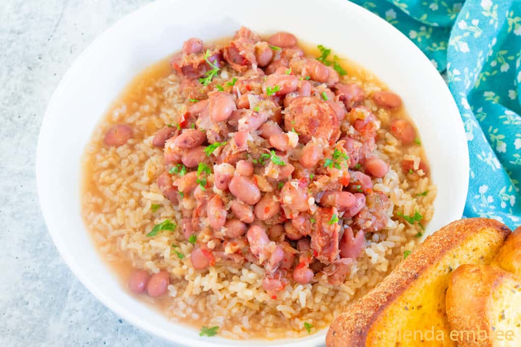 Red Beans and Rice served in a white ceramic bowl with a slice of toasted garlic bread.