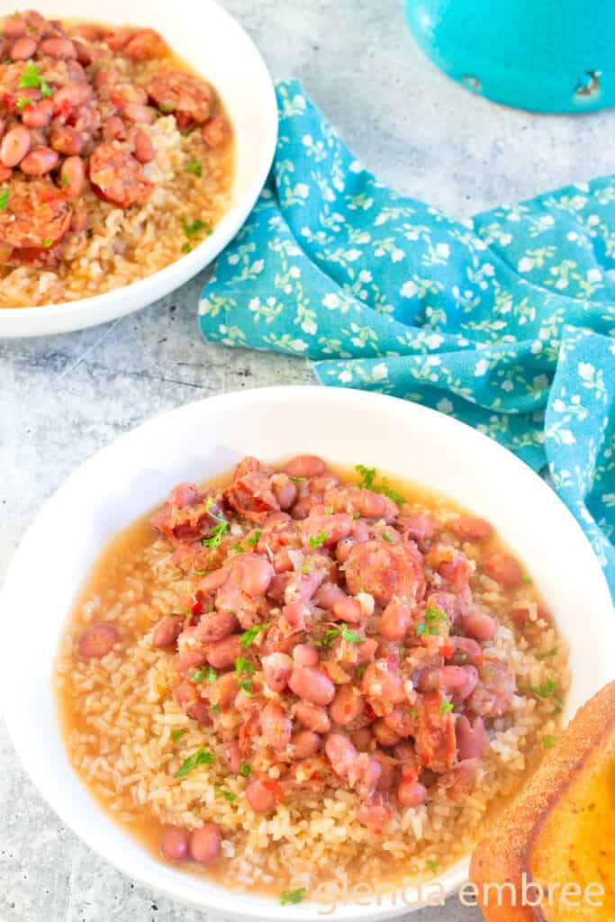 Two bowls of Red Beans and Rice white ceramic bowl swith a slice of toasted garlic bread.