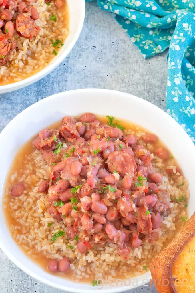 Two bowls of Red Beans and Rice white ceramic bowl swith a slice of toasted garlic bread.