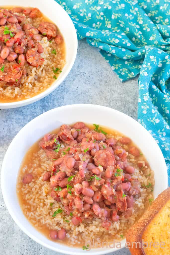 Two bowls of Red Beans and Rice white ceramic bowl swith a slice of toasted garlic bread.