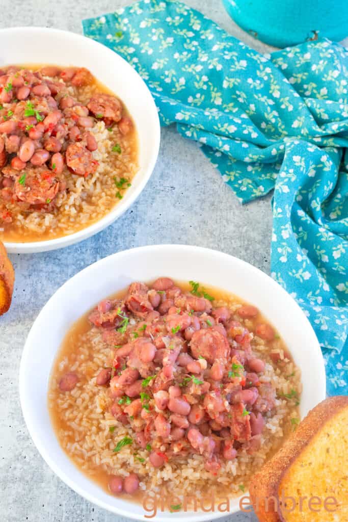 Two bowls of Red Beans and Rice white ceramic bowl swith a slice of toasted garlic bread.