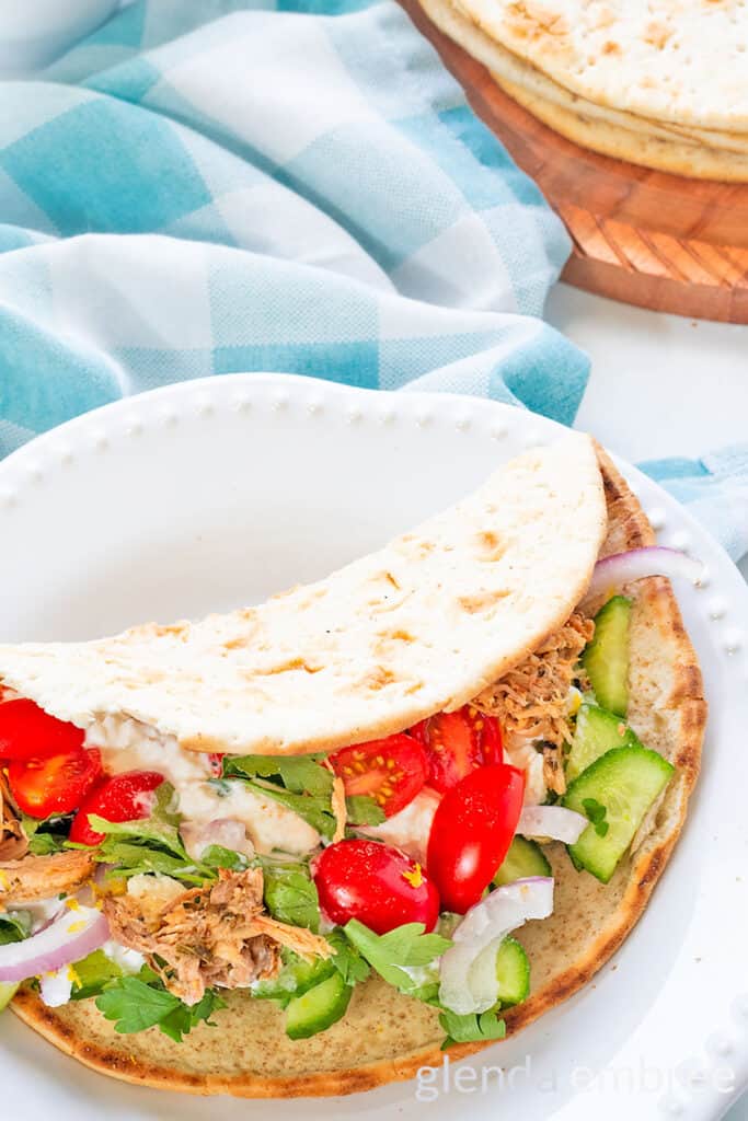 Leftover Slow cooker pork roast transformed into a pork souvlaki wrap with cucumbers, tomatoes and onions on a pita flat bread.
