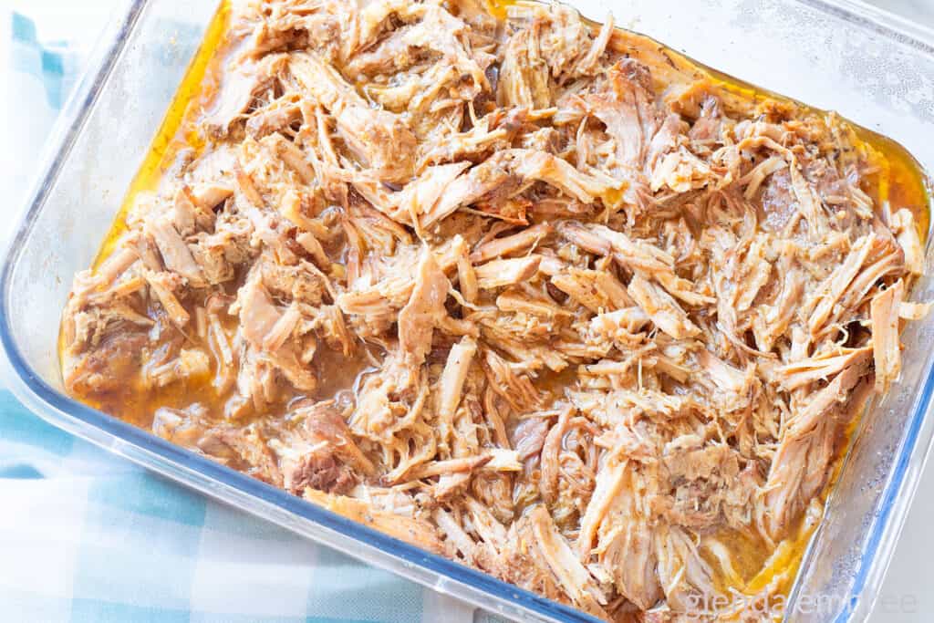 Leftover Slow Cooker Pork Roast and broth in a clear glass storage container.