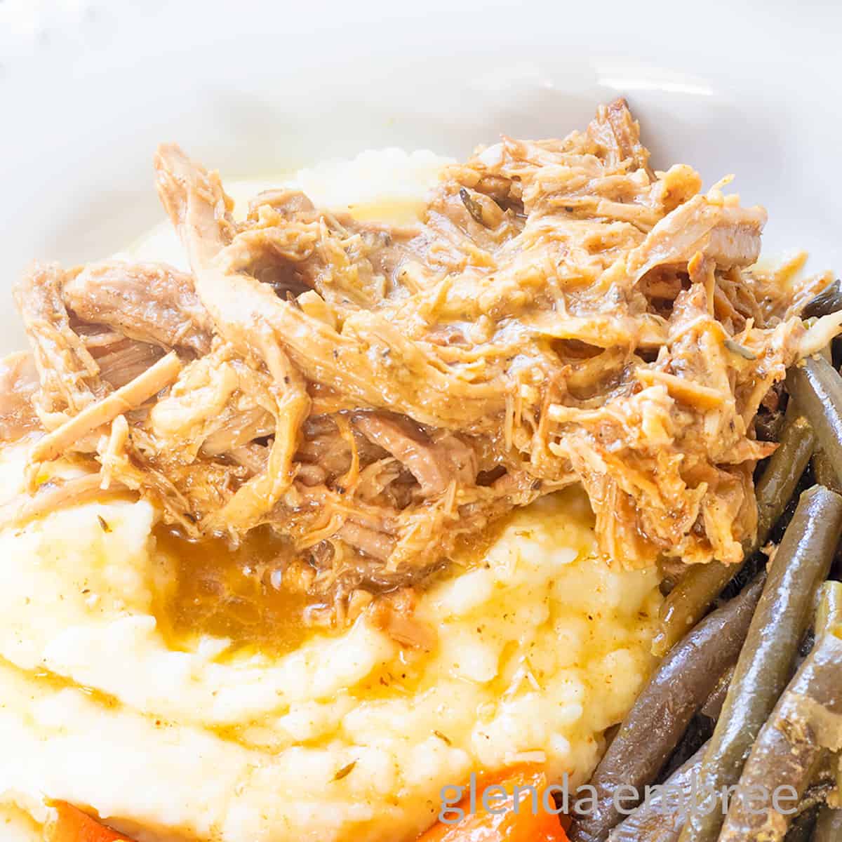 Slow Cooker Pork Roast on a white plate with mashed potatoes, carrots and green beans.